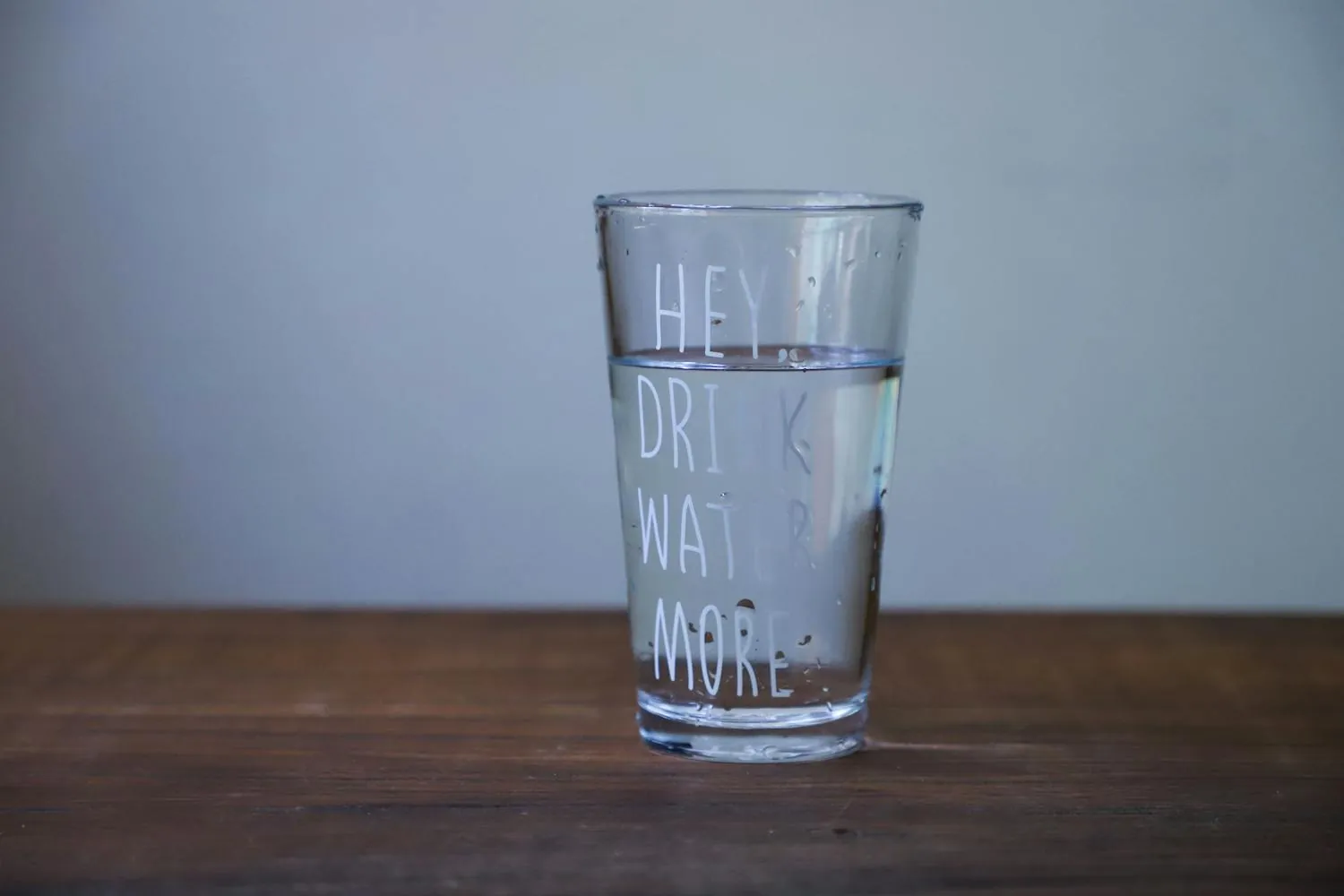 A glass of water on a wooden table encouraging healthy hydration