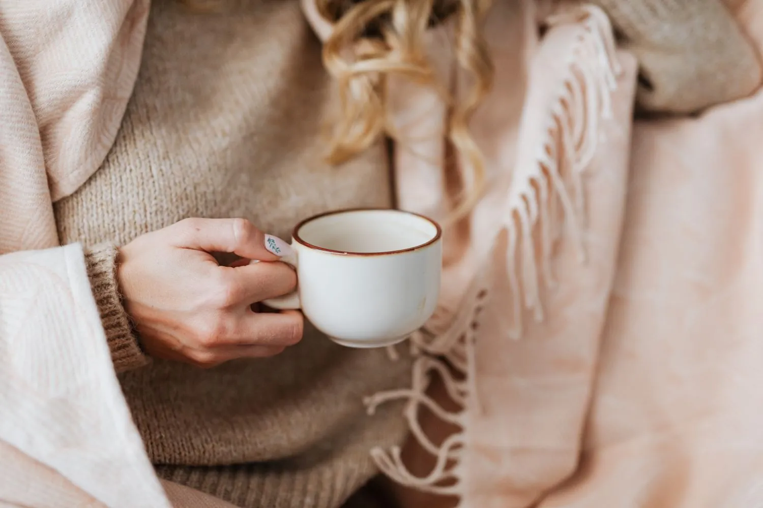 Hands cradling a warm cup in a cozy blanket, representing calm, attentive care